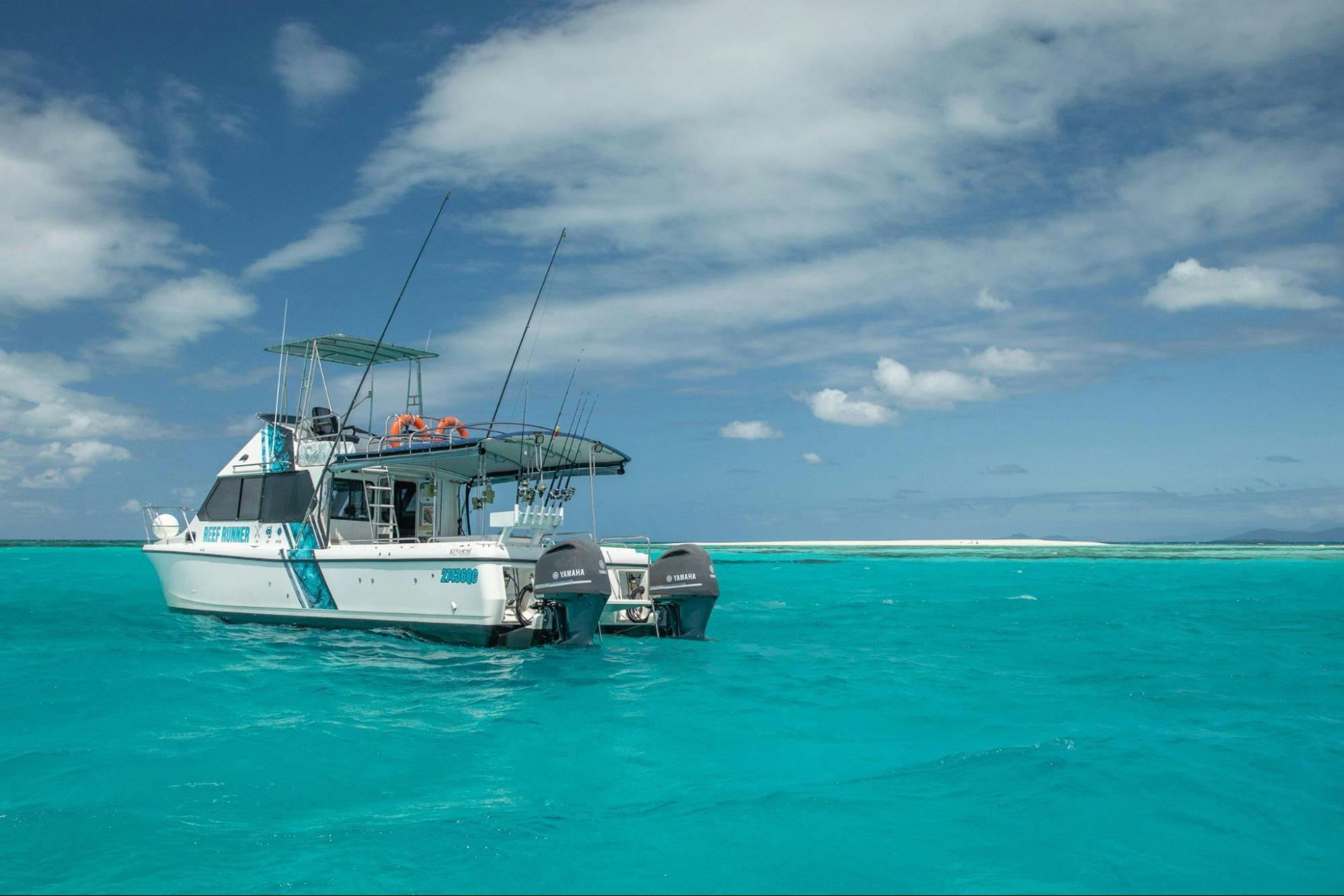 A fishing boat with two Yamaha motors is floating in bright blue water.