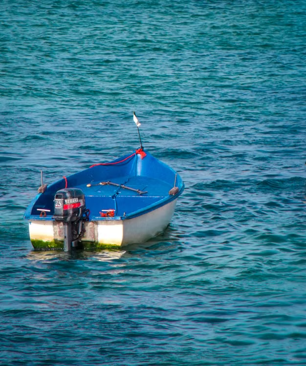 Used Yamaha outboard motor mounted on a small blue and white boat Used Yamaha outboard motor mounted on a small blue and white boat