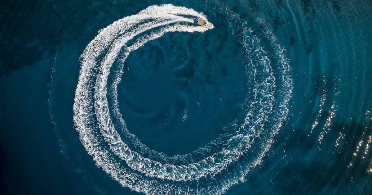 An aerial view of a luxurious speedboat in the Mediterranean Sea, making a circle from bubbles in the ocean. An aerial view of a luxurious speedboat in the Mediterranean Sea, making a circle from bubbles in the ocean.