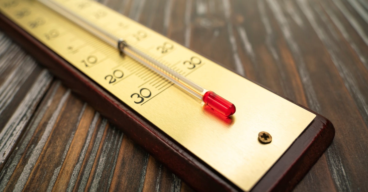 What Causes a Boat’s Outboard Motor To Overheat? A gold thermometer on a wooden surface, with a red liquid marker showing a temperature scale marked at 10, 20, and 30 degrees.