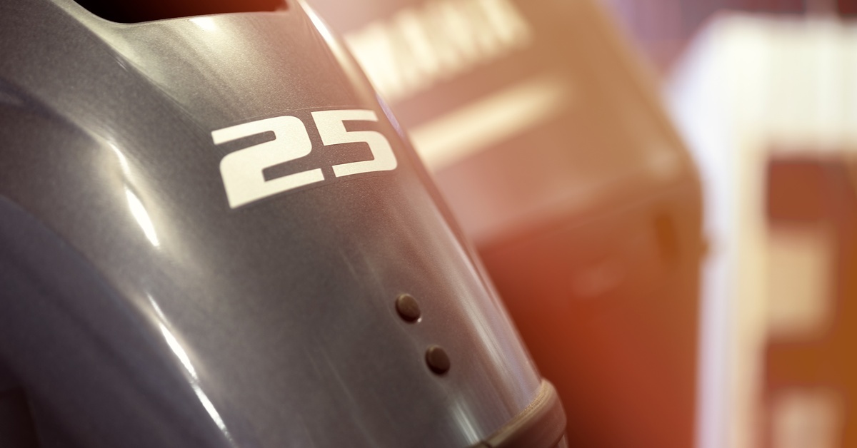 A black outboard motor with a white ‘25’ on the front shines under bright lights, with another motor in the background.
