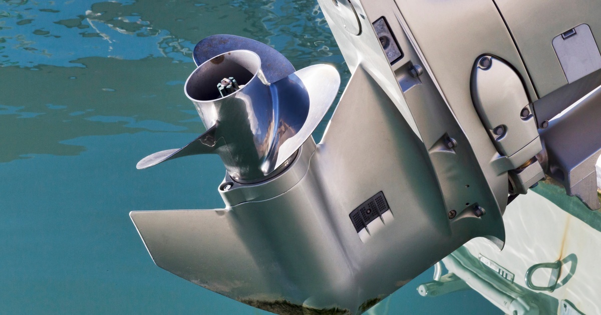 Fuel Stabilizers for Outboards: Do You Really Need Them? A shiny silver outboard motor propeller lifted out of the water water, displaying its clean blades and detailed housing.