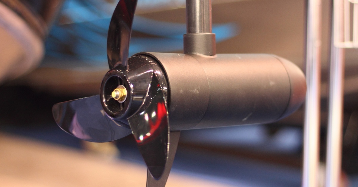 A close-up of the three-blade propellor of a black electric outboard motor out of water with the blackground blurred. A close-up of the three-blade propellor of a black electric outboard motor out of water with the blackground blurred.