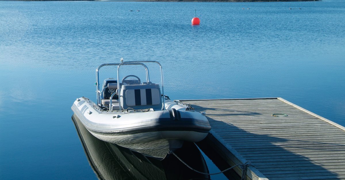 6 Reasons BRIG Is the Top Choice for RIBs A white and gray RIB floating in the water while tied to a small dock. An orange buoy is floating far behind the boat.