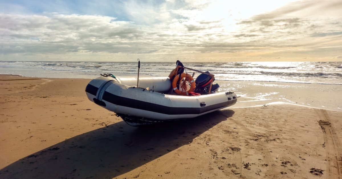 6 Reasons BRIG Is the Top Choice for RIBs A rigid inflatable boat with an outboard motor pulled up onto the shore. There are fishing and safety supplies in the boat.